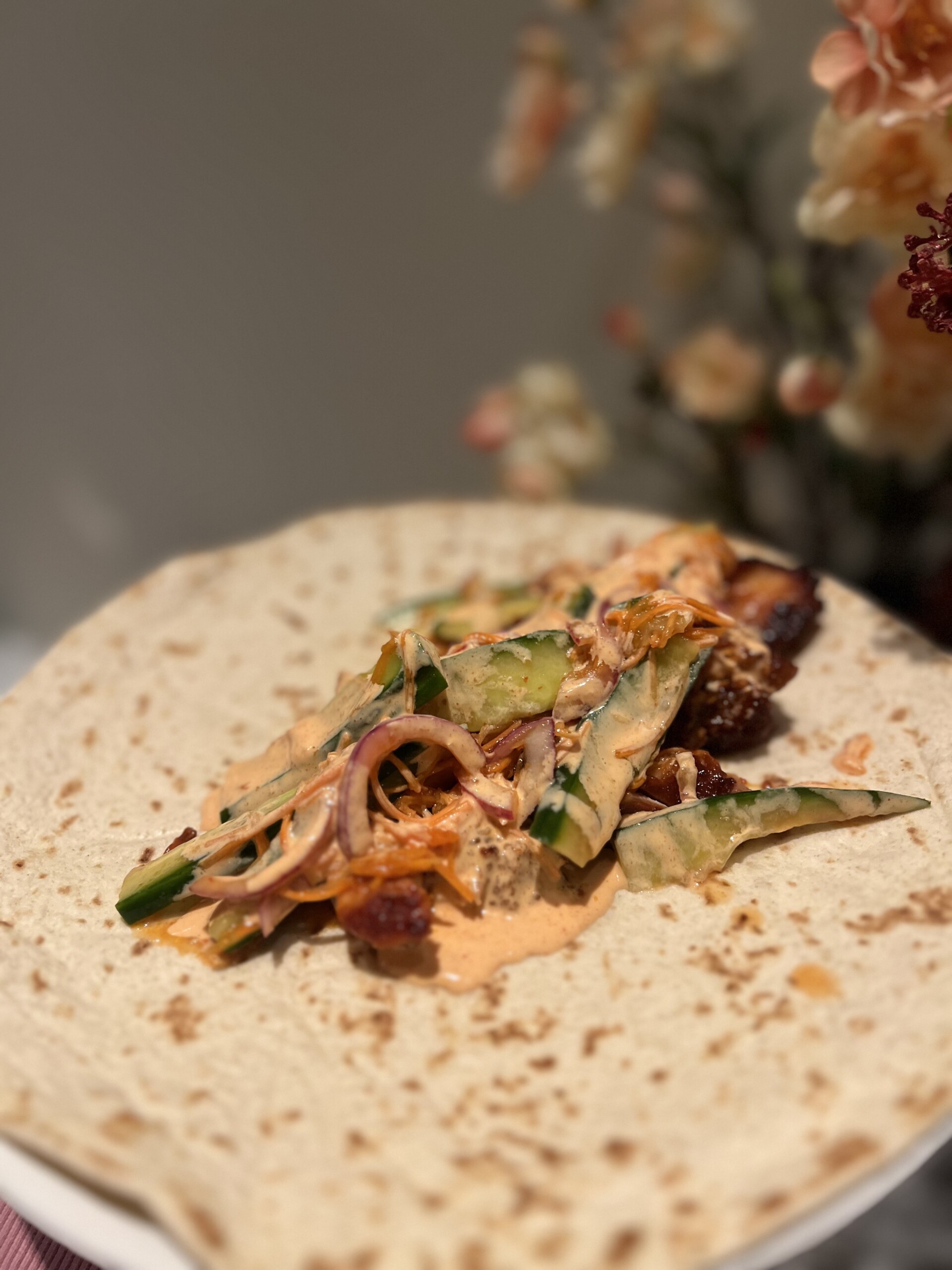koreaanse kip belegd op een wrap met een garnering van komkommer en Gochujang